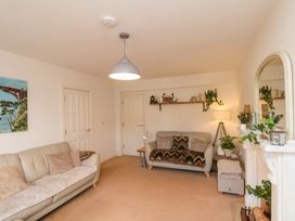 A living room with two sofas a shelf with decorations a floor lamp a painting and a mirror at Happy Days in Scarborough