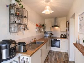 A kitchen with wooden countertops a stainless steel sink a wall-mounted metal rack with glassware and utensils and appliances on counters at Happy Days Scarborough