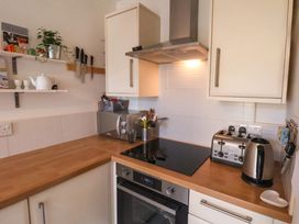A kitchen corner with a stove oven microwave toaster kettle knives and shelves at Happy Days in Scarborough
