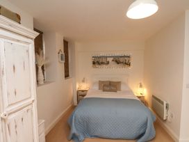 A bedroom with a double bed blue quilt bedside tables and a white wardrobe at Happy Days in Scarborough