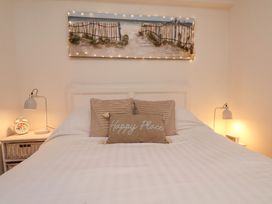 A bedroom with a double bed featuring three pillows and a painting above at Happy Days in Scarborough