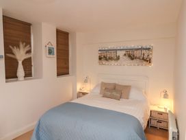 A bedroom with a bed with blue and white bedding two bedside tables with lamps and a wall painting above the bed at Happy Days in Scarborough