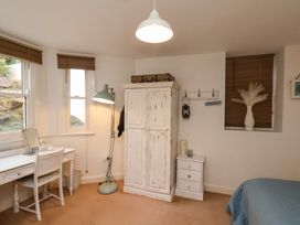 A bedroom with a white wardrobe a desk with chair and a bed with blue cover at Happy Days in Scarborough