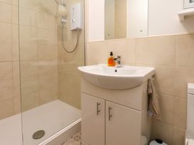 A bathroom with a shower area a white sink with cabinet and a mirror at Happy Days in Scarborough