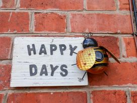 A bee decoration and a sign that says Happy Days on a brick wall at Happy Days in Scarborough
