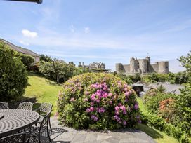 A garden with flowering bush and patio furniture overlooking a castle at Bryn Awelon in Harlech