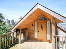 A wooden porch with a front door and railing with a castle in the background at Bryn Awelon in Harlech