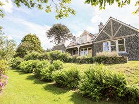 A stone house with a grass lawn and bushes in the garden at Bryn Awelon in Harlech