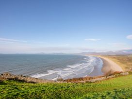 A coastline with waves along a sandy beach and grassy foreground at Bryn Awelon in Harlech