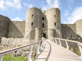 A stone castle with two round towers and a wooden bridge leading to the entrance at Bryn Awelon in Harlech
