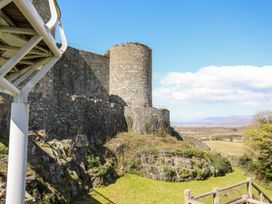 Stone castle wall with round tower and grassy area with hills in the background at Bryn Awelon in Harlech