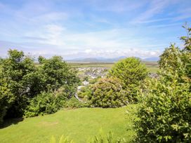 A garden with lush green grass and shrubs overlooking a town and distant mountains at Bryn Awelon in Harlech