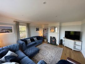 A living room with blue sofas a patterned rug a fireplace and a television at Bryn Awelon in Harlech