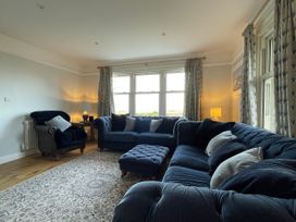 A living room with blue sofas armchair ottoman and curtains at Bryn Awelon in Harlech
