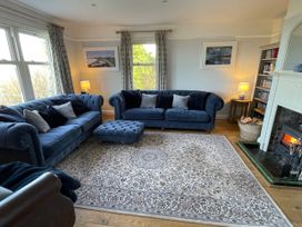A living room with blue sofas a patterned rug a fireplace and bookshelves at Bryn Awelon in Harlech