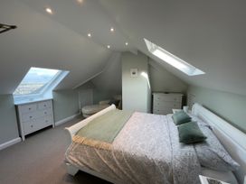 A bedroom with a double bed two dressers a chaise lounge and skylight windows at Bryn Awelon in Harlech