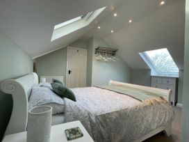 A bedroom with a bed side table a bed two skylight windows a chest of drawers and a wall mounted coat rack with hangers at Bryn Awelon Harlech