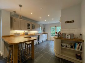 A kitchen with wooden countertops bar stools cabinets and a tiled floor at Bryn Awelon in Harlech