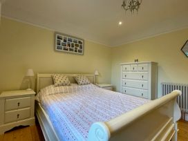 A bedroom with a bed a dresser two bedside tables with lamps and a framed photo collage on the wall at Bryn Awelon in Harlech