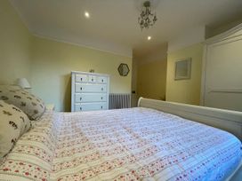 A bedroom with a bed covered with floral patterned bedding a white dresser a radiator a chandelier and a wardrobe at Bryn Awelon in Harlech