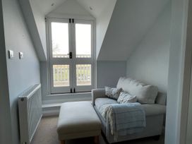 A small room with a sofa, ottoman, radiator, and double doors leading outside at Bryn Awelon in Harlech
