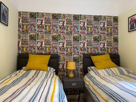 A bedroom with two single beds separated by a nightstand with a lamp and a comic book themed wallpaper behind the beds at Bryn Awelon in Harlech