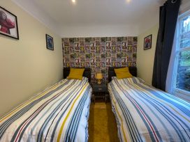 A bedroom with two single beds with striped bedding and yellow pillows a comic-themed wallpaper behind the beds and framed pictures on the walls at Bryn Awelon in Harlech