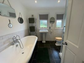 A bathroom with a bathtub sink toilet and three mirrors at Bryn Awelon in Harlech