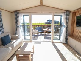 A living room with a sofa and sliding doors leading to a deck at Fir Lodge in Whitby