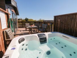 A hot tub on a wooden deck with garden chairs and a table at Fir Lodge in Whitby
