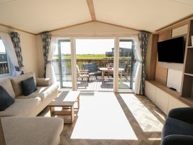 A living room with a sliding door leading to the deck at Fir Lodge in Whitby