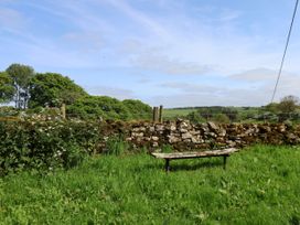 A bench near a stone wall and trees at Cherry Blossom Lodge in Whitby