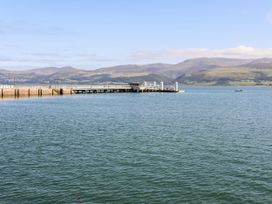 A pier extending into water with mountains in the background at Gorse Hill, Rhosneigr