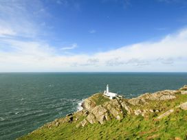 A lighthouse on a rocky coastline near the ocean at Gorse Hill in Rhosneigr