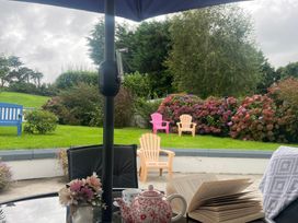 An outdoor seating area with a teapot and book on a table at Dromclough Farmhouse in Dromclough near Listowel, County Kerry