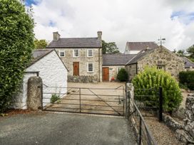 A stone house with a gravel entrance and gates at Tyddyn Iolyn in Benllech