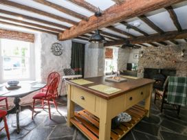 A kitchen with a wooden table and red chairs at Tyddyn Iolyn in Benllech