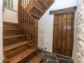 A hallway with staircase and wooden door at Tyddyn Iolyn in Benllech