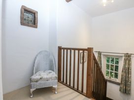 A hallway with a chair and staircase at Tyddyn Iolyn in Benllech