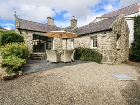A stone building with an outdoor seating area at Tyddyn Iolyn Benllech