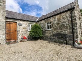 An outdoor area with a bench and a stone building at Tyddyn Iolyn in Benllech