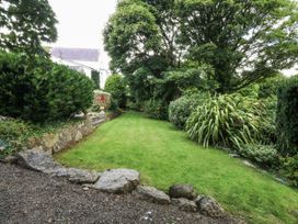 A garden with grass and trees at Tyddyn Iolyn in Benllech