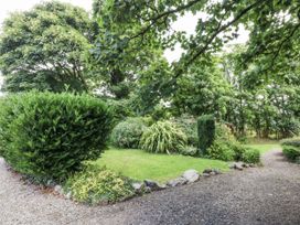 A garden with bushes and a gravel path at Tyddyn Iolyn in Benllech