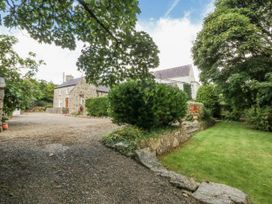 A garden view with a house and trees at Tyddyn Iolyn in Benllech