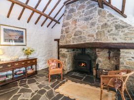 A living room with a stone fireplace and wicker chairs at Tyddyn Iolyn in Benllech