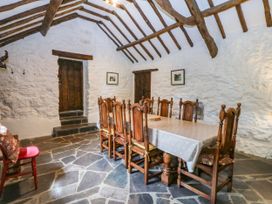 A dining room with wooden furniture and a stone floor at Tyddyn Iolyn Benllech
