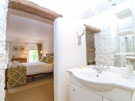A bathroom with a mirror and sink leading to a bedroom at Tyddyn Iolyn in Benllech