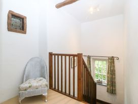 A staircase with a wooden railing and a round chair at Tyddyn Iolyn in Benllech