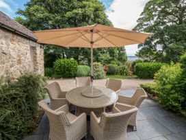 An outdoor seating area with a table and chairs under an umbrella at Tyddyn Iolyn Benllech