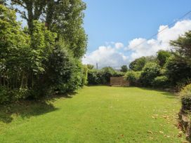 A garden with grass and trees at Tyddyn Iolyn in Benllech